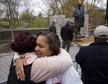 In this Tuesday, April 17, 2018, file photo, Dr. Bernadith Russell hugs a friend as the statue of Dr. J. Marion Sims, is removed from New York's Central Park. (Mark Lennihan/AP Photo, File)