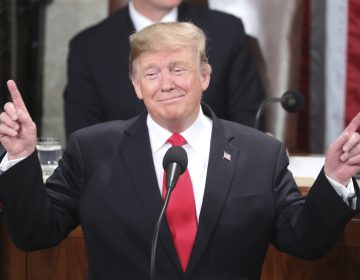 President Donald Trump gestures as a conductor as people in the chamber sing 