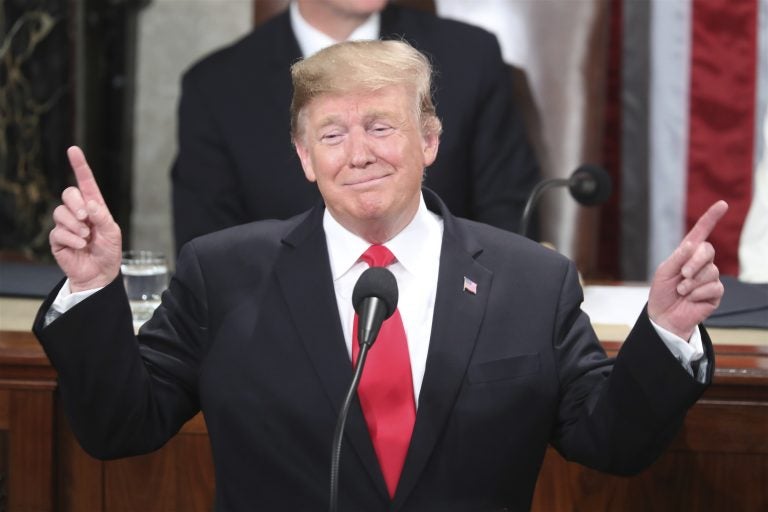 President Donald Trump gestures as a conductor as people in the chamber sing 