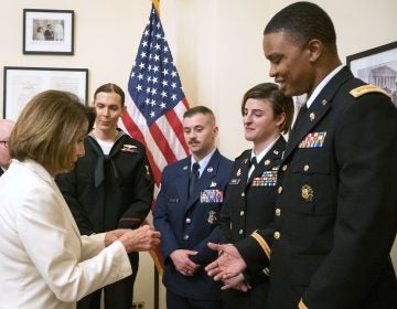 In this Tuesday, Feb. 5, 2019 photo released by her office, Speaker of the House Nancy Pelosi, D-Calif., left, gives challenge coins to U.S. Army Maj. Ian Brown, right, and other military service members to thank them for their service, in her office at the Capitol following the State of the Union address in Washington. Brown, 38, is a two-time Bronze Star recipient who transitioned from female to male while advising the Army's deputy chief of staff in operations and planning. (Julio Obscura/Office of the Speaker of the House Nancy Pelosi via AP)