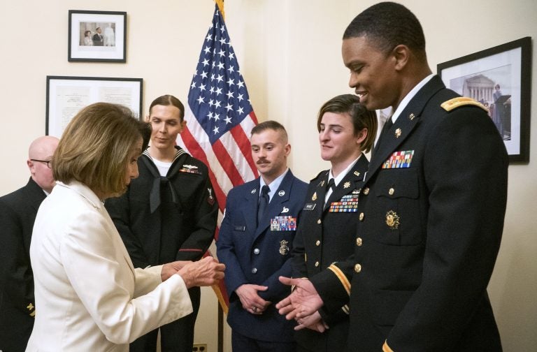 In this Tuesday, Feb. 5, 2019 photo released by her office, Speaker of the House Nancy Pelosi, D-Calif., left, gives challenge coins to U.S. Army Maj. Ian Brown, right, and other military service members to thank them for their service, in her office at the Capitol following the State of the Union address in Washington. Brown, 38, is a two-time Bronze Star recipient who transitioned from female to male while advising the Army's deputy chief of staff in operations and planning. (Julio Obscura/Office of the Speaker of the House Nancy Pelosi via AP)