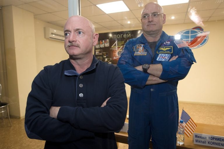 In this March 26, 2015 file photo, U.S. astronaut Scott Kelly, (right), crew member of the mission to the International Space Station, stands behind glass in a quarantine room, behind his brother, Mark Kelly, also an astronaut, after a news conference in the Russian-leased Baikonur, Kazakhstan cosmodrome. Nearly a year in space put Scott Kelly's immune system on high alert and changed the activity of some of his genes compared to his Earth-bound identical twin, according to a report released on Friday, Feb. 15, 2019. (Dmitry Lovetsky/AP Photo)