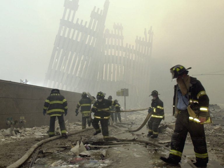 In this Sept. 11, 2001 file photo, with the skeleton of the World Trade Center twin towers in the background, New York City firefighters work amid debris on Cortlandt St. after the terrorist attacks.  (Mark Lennihan/AP Photo, File)