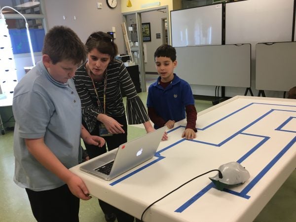 Teacher Laurie Drumm helps students program their robot to navigate a maze. (Mark Eichmann/WHYY)