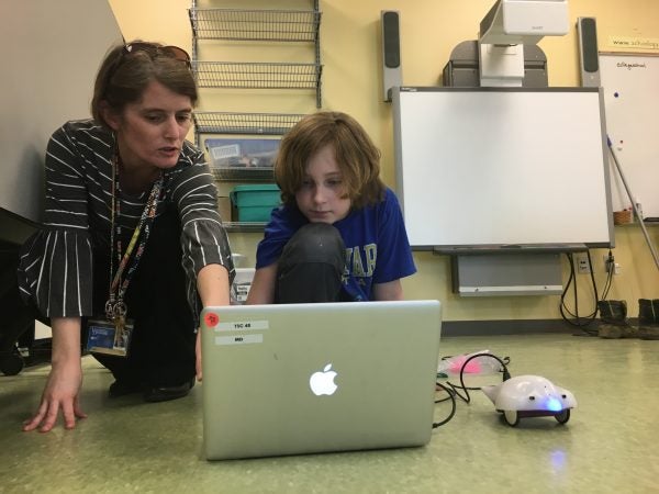 Teacher Laurie Drumm helps students program their robot to navigate a maze. (Mark Eichmann/WHYY)