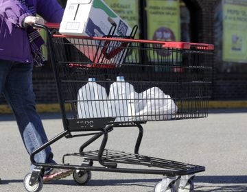 In this Friday, Feb. 26, 2016 photo, a woman leaves a Tops supermarket with bottled water that is being supplied to residents in Hoosick Falls, N.Y. PFOA, long used in the manufacuring of Teflon pans, Gore-Tex jackets, ski wax, and many other products has turned up in the water in factory towns around the country like Hoosick Falls, impacting drinking water. (AP Photo/Mike Groll)