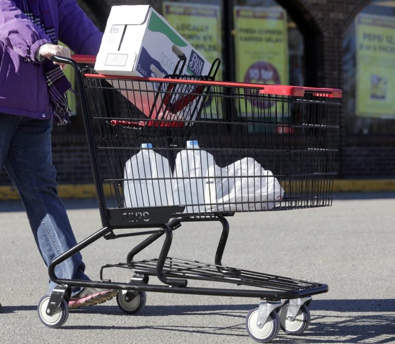 In this Friday, Feb. 26, 2016 photo, a woman leaves a Tops supermarket with bottled water that is being supplied to residents in Hoosick Falls, N.Y. PFOA, long used in the manufacuring of Teflon pans, Gore-Tex jackets, ski wax, and many other products has turned up in the water in factory towns around the country like Hoosick Falls, impacting drinking water. (AP Photo/Mike Groll)