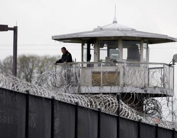 A solitary corrections officer looks out from a tower at one corner of the state prison in Camp Hill. (Carolyn Kaster/AP Photo) 