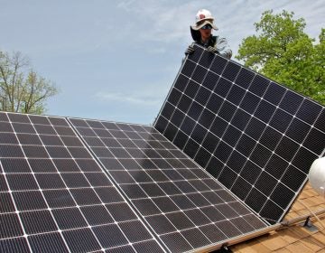 Patrick Whittaker of Solar States installs solar panels on the roof of a home in Bryn Mawr. (Emma Lee/WHYY)