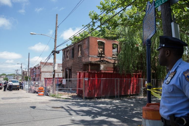 A police officer secures the block as investigators survey a demolition site that turned deadly at the corner of Jefferson and Bailey Streets in North Philadelphia on June 04, 2018.  (Lindsay Lazarski/WHYY)