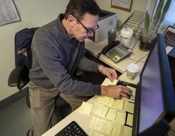 Army veteran Chris Riga survived multiple blast injuries in deployments in Afghanistan and Iraq. He rearranges sticky notes on his desk to assist him in remembering tasks he has to do throughout the day at his job as patient experience coordinator at the Northampton VA Medical Center in Leeds, Mass. (Jesse Costa/WBUR)