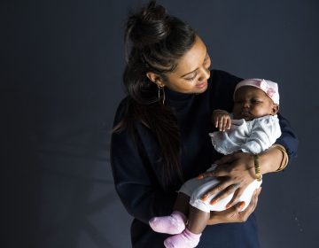 Midwife Asasiya Muhammad poses for a portrait with two-month-old Winter Nimmons at her practice, Inner Circle Midwifery, on February 9. Muhammad delivered Nimmons two months ago and had to resuscitate Winter when she was born not breathing. (Rachel Wisniewski/WHYY)