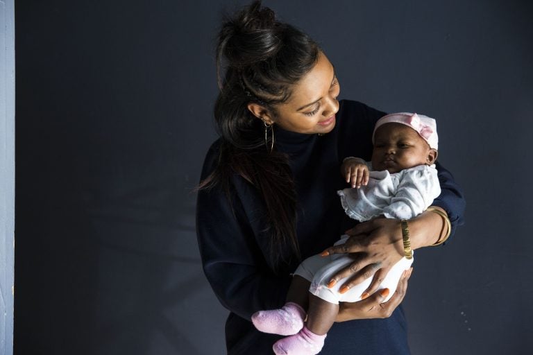 Midwife Asasiya Muhammad poses for a portrait with two-month-old Winter Nimmons at her practice, Inner Circle Midwifery, on February 9. Muhammad delivered Nimmons two months ago and had to resuscitate Winter when she was born not breathing. (Rachel Wisniewski/WHYY)