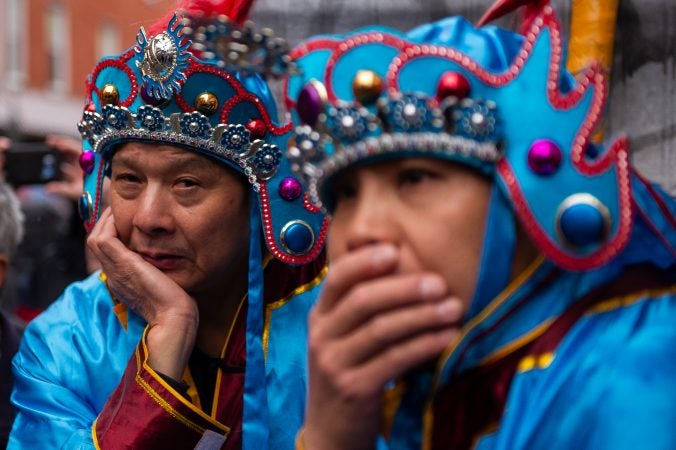 Wearing costumes of their own, two men watch a traditional Chinese opera performance during the Hoyu Folk Culture Festival in Chinatown on Sunday, March 31, 2019. (Kriston Jae Bethel for WHYY)