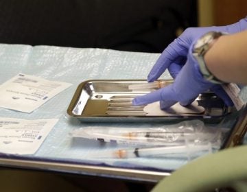 A health care worker prepares syringes