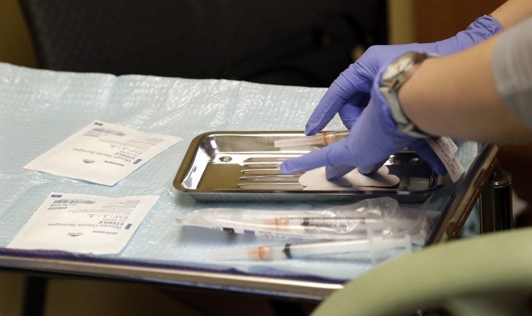 A health care worker prepares syringes