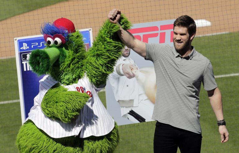 Bryce Harper stands with the Philadelphia Phillies mascot Phanatic before being introduced as a Phillies player during a news conference at the team's spring training baseball facility, Saturday, March 2, 2019, in Clearwater, Fla. Harper and the Phillies agreed to a $330 million, 13-year contract, the largest deal in baseball history. (Lynne Sladky/AP Photo)