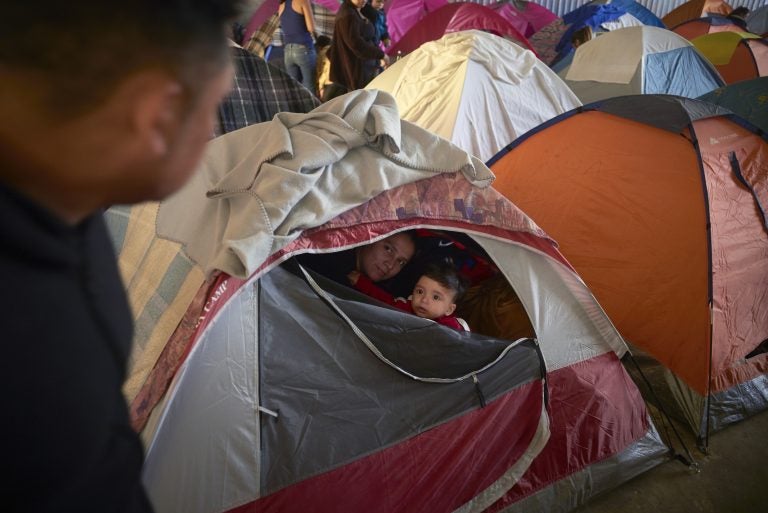 In this March 5, 2019, image, Ruth Aracely Monroy, (center), looks out of the family's tent alongside her 10-month-old son, Joshua, as her husband, Juan Carlos Perla, (left), passes inside a shelter for migrants in Tijuana, Mexico. (Gregory Bull/AP Photo)