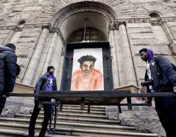 Farooq Al-Said, left, Jasiri X, center, and Jarrion Manning, right, hold a memorial display with a drawing of Antwon Rose II in front of the court house on the first day of the trial for Michael Rosfeld, a former police officer in East Pittsburgh, Pa., begins on Tuesday, March 19, 2019, in Pittsburgh. (Keith Srakocic/AP Photo)