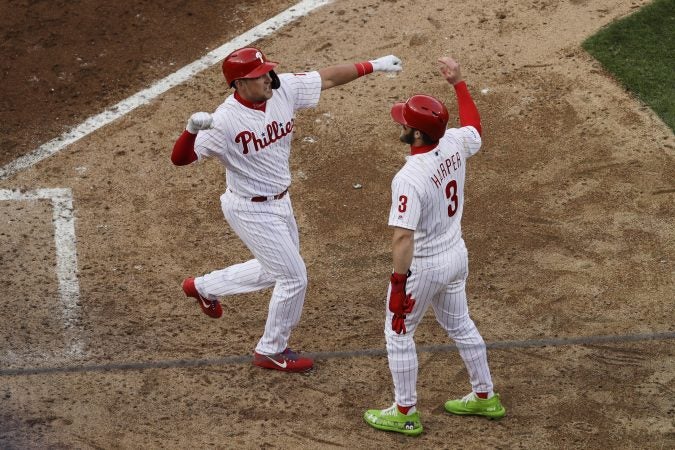 Philadelphia Phillies' Rhys Hoskins, left, celebrates his grand slam with Bryce Harper in the seventh inning of an opening day baseball game against the Atlanta Braves, Thursday, March 28, 2019, in Philadelphia. (AP Photo/Matt Rourke)