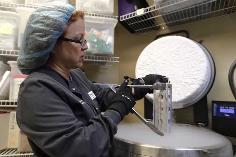 Medical tech removes a container with frozen embryos and sperm being stored in liquid nitrogen at a fertility clinic. (Lynne Sladky/ AP Photo)