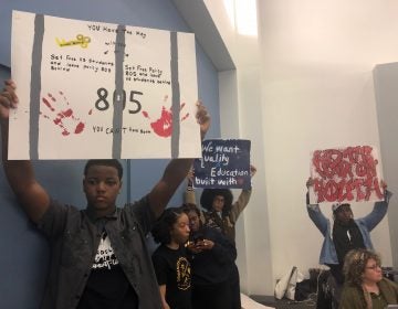 Students hold up signs denouncing Policy 805 prior to the Board’s yes vote that led students and faculty to temporarily shut down the school board meeting.  (Darryl Murphy/WHYY)