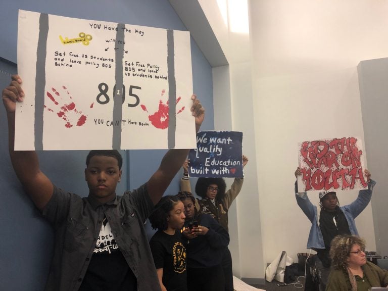 Students hold up signs denouncing Policy 805 prior to the Board’s yes vote that led students and faculty to temporarily shut down the school board meeting.  (Darryl Murphy/WHYY)