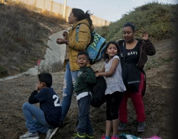 Honduran migrants react as they surrender to the U.S. Border Patrol after crossing the border wall into the United States. According to new federal data, the number of migrants apprehended crossing the border in recent months has surged.
(Ramon Espinosa/AP)