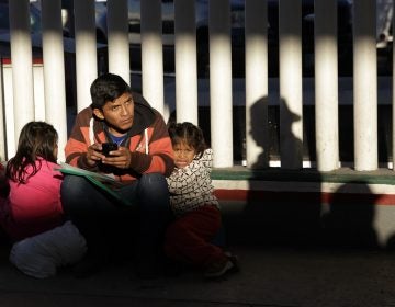 A migrant and his children wait to hear if their number is called to apply for asylum in the United States, at the border in Tijuana, Mexico. (Gregory Bull/AP)