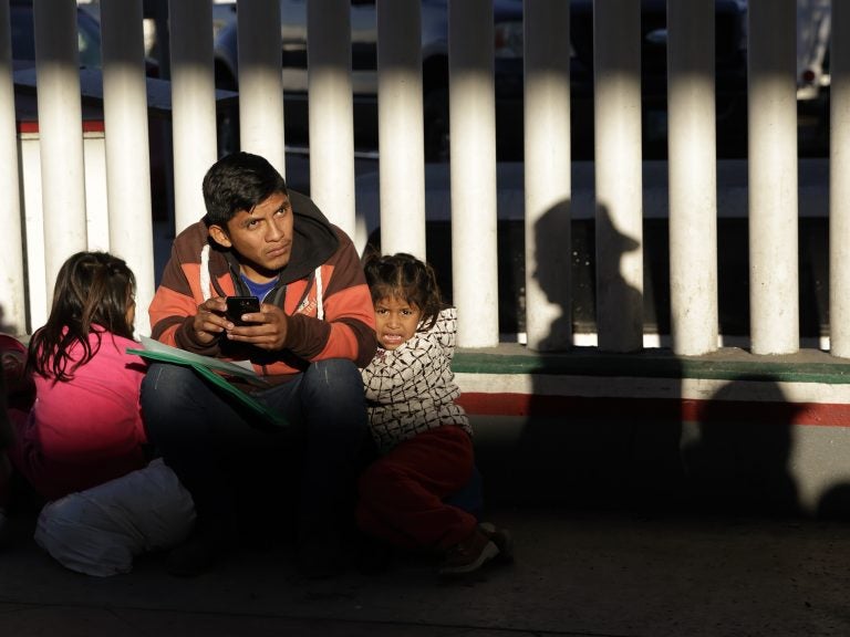 A migrant and his children wait to hear if their number is called to apply for asylum in the United States, at the border in Tijuana, Mexico. (Gregory Bull/AP)