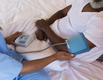Close-up of African American female doctor measuring blood press Close-up of African American female doctor measuring blood pressure of senior African American man at home