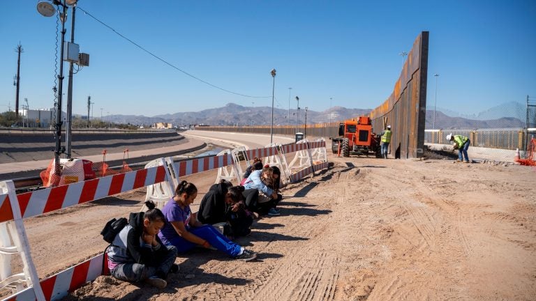 Salvadoran migrants wait for transportation after turning themselves in to U.S. Border Patrol agents in El Paso, Texas — where a border fence is under construction. The Pentagon says it will spend up to $1 billion to help build the fence. (Paul Ratje /AFP/Getty Images)