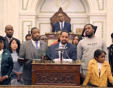 Meek Mill (right) and his son listen as Pennsylvania state Sen. Sharif Street (center) presents a state resolution in his honor. (Tom MacDonald/WHYY)