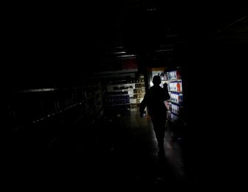 A worker inspects damage in a supermarket in Caracas on Sunday after it was looted during a days-long blackout in Venezuela.
(Carlos Garcia Rawlins/Reuters)