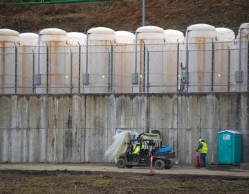 Once it is safe to remove the spent fuel from the pool, it's stored outside in metal casks. They are lined up on a concrete base, behind razor wire and against a hillside near the power plant. (Olivia Sun/NPR)