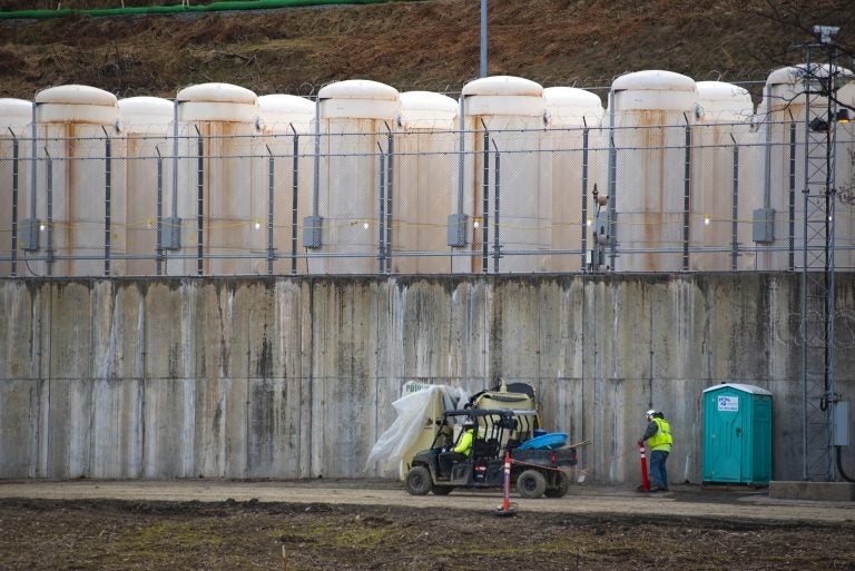 Once it is safe to remove the spent fuel from the pool, it's stored outside in metal casks. They are lined up on a concrete base, behind razor wire and against a hillside near the power plant. (Olivia Sun/NPR)