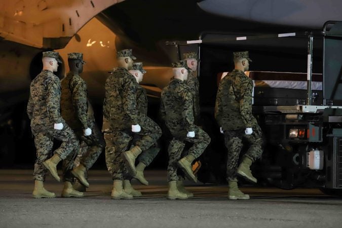 A U.S. Marine Corps carry team walks to the remains of Staff Sgt. Christopher K.A. Slutman during a dignified transfer at Dover Air Force Base Thursday, Apr. 11. (Saquan Stimpson for WHYY)