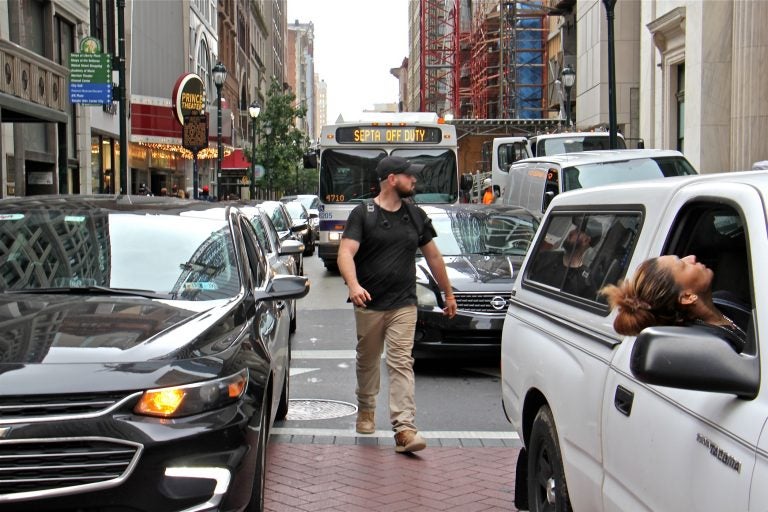 A pedestrian threads his way through traffic at the intersection of Broad and Chestnut streets. (Emma Lee/WHYY)