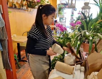 An employee at the Coco Thai Bistro lays out some of the shop's new biodegradable products.  (Xavier Lopez for WHYY)