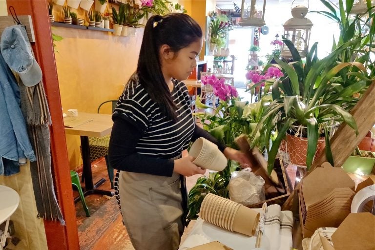 An employee at the Coco Thai Bistro lays out some of the shop's new biodegradable products.  (Xavier Lopez for WHYY)