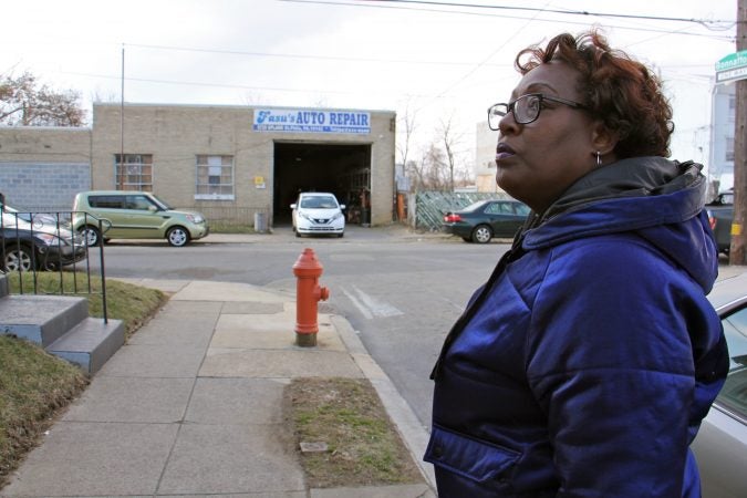 Tracey Gordon stands in a residential block of Bonnaffon Street, which is bookended by auto repair shops. (Emma Lee/WHYY)