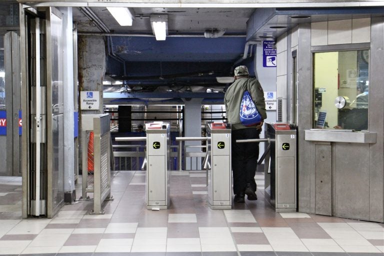 A SEPTA rider passes through the turnstile at the 8th and Market station. (Emma Lee/WHYY)