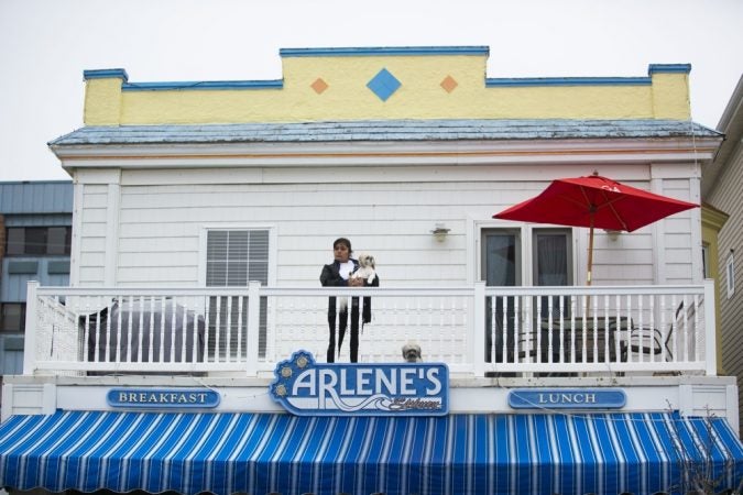 A spectator watches from a balcony on Asbury Avenue as hundreds of basset  hounds march down the street during BoardWaddle on Saturday, April 13, 2019, in Ocean City. (Miguel Martinez for WHYY)