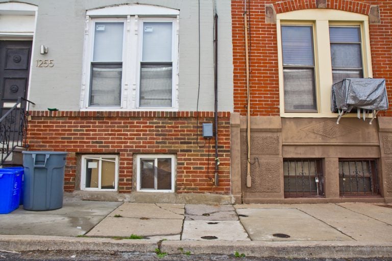 Sidewalks are shown on a block with rowhomes that are slanted and cracked.