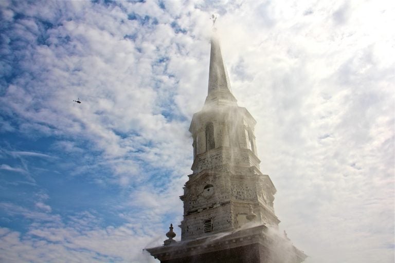 The spire of Christ Church in Od City fades behind a cascade of water, part of a fire protection system installed to prevent the kind of calamity that occured at Notre Dame cathedral in Paris. (Emma Lee/WHYY)