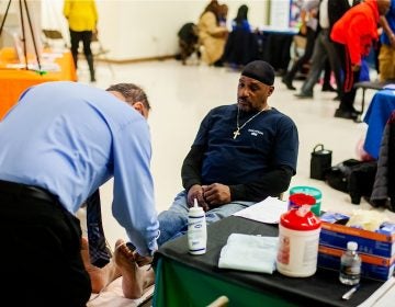 Dr. Ronald Renzi performs an ultrasound on Russell Davis to check on blood circulation in screenings for peripheral vascular disease during a health and wellness clinic at Enon Tabernacle Baptist Church in Mount Airy. (Brad Larrison for WHYY)