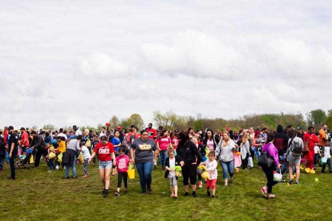 Children and parents left the River Fields in Northeast Philadelphia with their hall of Easter eggs after a helicopter dropped an estimated 30,000 eggs. (Brad Larrison for WHYY)