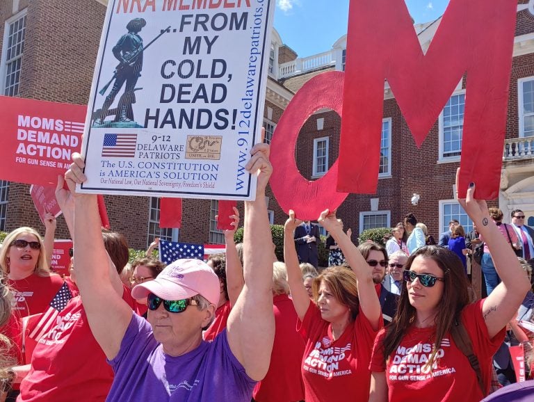 An NRA supporter holds up a sign in front of gun-control activists in front of the Delaware State Capitol building in Dover, Del., Wednesday. (Zoe Read/WHYY)