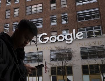 FILE - In this Dec. 17, 2018, file photo, a man using a mobile phone walks past Google offices in New York. Executives from Google and Facebook are facing Congress Tuesday, April 8, 2019, to answer questions about their role in the hate crimes and the rise of white nationalism in the U.S. (AP Photo/Mark Lennihan, File)