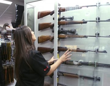 In this Wednesday, Oct. 4, 2017 file photo, a salesperson checks rifles in a gun shop display in Sydney, Australia. A documentary aired in March 2019 by Al Jazeera reported officials with Australia's far-right One Nation party met with two National Rifle Association representatives and other gun-rights advocates seeking money to undermine Australian gun laws. (Rick Rycroft/AP Photo)
